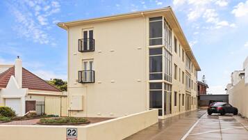 A residential building with a flat facade, a balcony, and a parking area marked with the number 22.