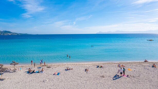 A beach with clear blue water, people sunbathing, and umbrellas. - VORAMAR 1 - Fabulous beachfront apartment. Free Wi-Fi. (Alcúdia)