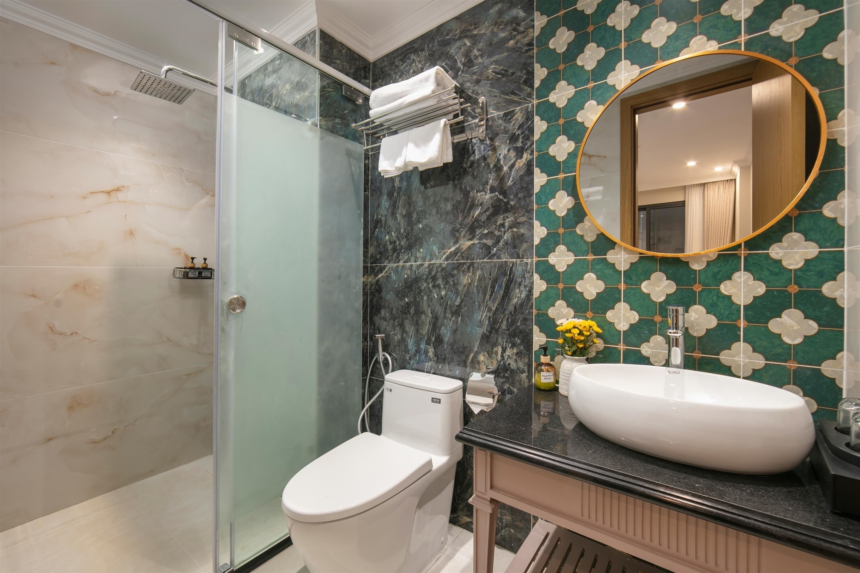 A bathroom with a glass-enclosed shower, a white toilet, a sink with a mirror, and a decorative tile backsplash.