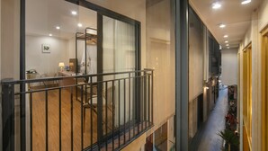 A modern interior with a balcony, a dining area, and a narrow corridor with bicycles.