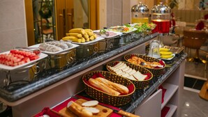 A buffet with various food items including fruits, pastries, and sandwiches.