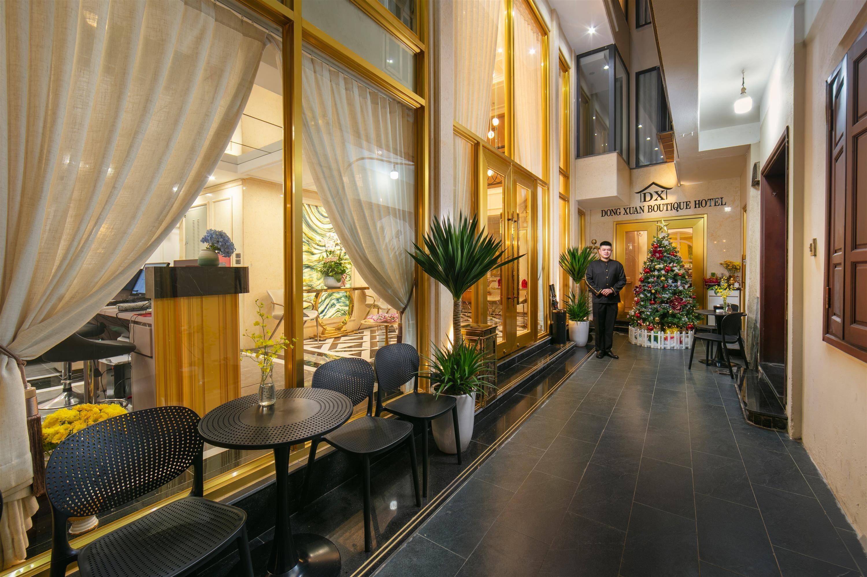 A hotel lobby with a Christmas tree, a concierge, and a staircase leading to an upper floor.