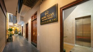 A hotel corridor with a Christmas tree, wooden doors, and an elevator.