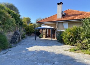 Un chemin de pierres mène à une maison avec un toit en tuiles et une cheminée.