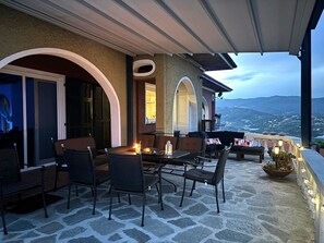Une terrasse extérieure avec un sol en pierre, une table et des chaises, et une vue sur le paysage.