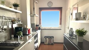 A compact kitchen with white cabinets, a black countertop, and a window with a view. - Villa with pool and terrace sea view | V02 (Imperia)