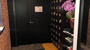 A hallway with a shoe rack, a door with a no-smoking sign, and a potted orchid. - Guest House Siesta (Tokyo)