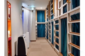 A corridor with built-in shelving units, a radiator, and a black object on the floor. - Guest House Siesta (Tokyo)