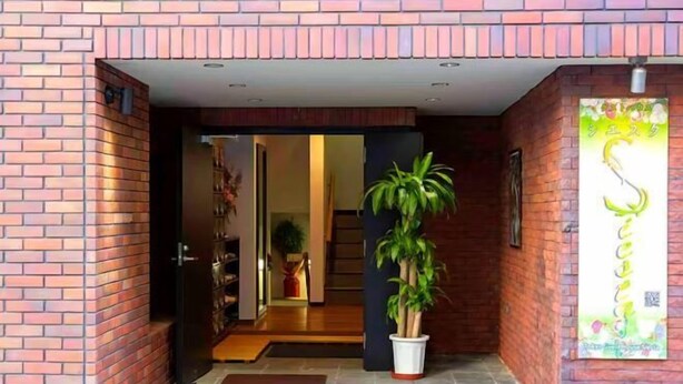A brick exterior with a potted plant in the entrance. - Guest House Siesta (Tokyo)