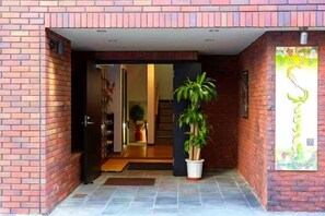 A brick exterior with a potted plant in the entrance. - Guest House Siesta (Tokyo)
