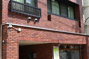 Un bâtiment en briques doté d’un balcon, d’une fenêtre avec une grille en métal et d’une porte.