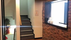 A staircase leading to the first floor, a brick wall, and a window with blinds. - Guest House Siesta (Tokyo)
