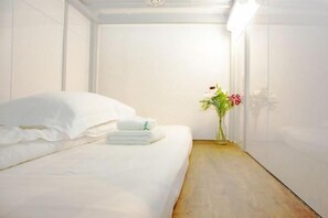 Ein Hotelzimmer mit Bett, Holzboden und einer Blumenvase.