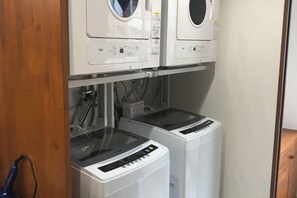 Une buanderie équipée de deux machines à laver à chargement frontal et de deux séchoirs à chargement par le haut.