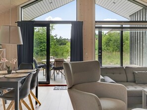 A modern interior with a dining area, sofa, and large windows offering a view of greenery. - "Jelisaveta" - 45km from the sea by Interhome (Ejstrupholm)