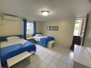 A hotel room with two beds, a desk, a chair, a window with curtains, a ceiling light, and a mirror on the wall. - 3-bedroom Coastal Escape in lovely Christ Church with Wi-Fi, AC (Bridgetown)
