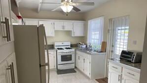 Une cuisine avec des meubles blancs, une cuisinière, un évier et un grille-pain.