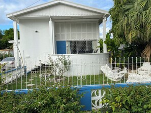 A white two-story house with a blue door, surrounded by a white fence with blue accents. - 3-bedroom Coastal Escape in lovely Christ Church with Wi-Fi, AC (Bridgetown)