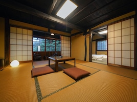 Una habitación tradicional japonesa con suelo de tatami, una mesa baja y puertas correderas.