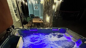 A hot tub with blue lighting, surrounded by a wooden deck and a tree. - Relaxing 3-bedroom house in Wareham by the water (Wareham)