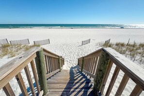 A wooden staircase leading to a sandy beach with a clear blue sky.