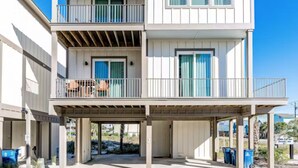 A two-story beachfront property with a covered patio, balconies, and a garage.