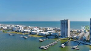 An aerial view of a coastal hotel area with multiple buildings, docks, and a marina.