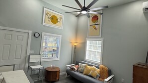 A modern living room with a grey sofa, a dining table, and a ceiling fan. - Wandering Inn FY25 Build. (Monroe)