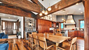 Spaziosa sala da pranzo con un grande tavolo e sedie in legno, cucina con mobili in legno e camino in pietra.