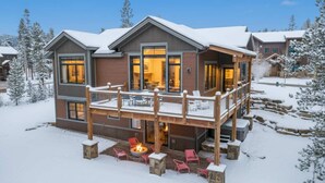 En tvåvåningsstuga med en veranda, en eldstad och utsikt över det snötäckta landskapet.