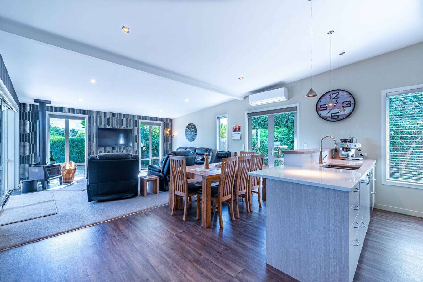 A modern kitchen with a dining area, large windows, and a built-in grill.
