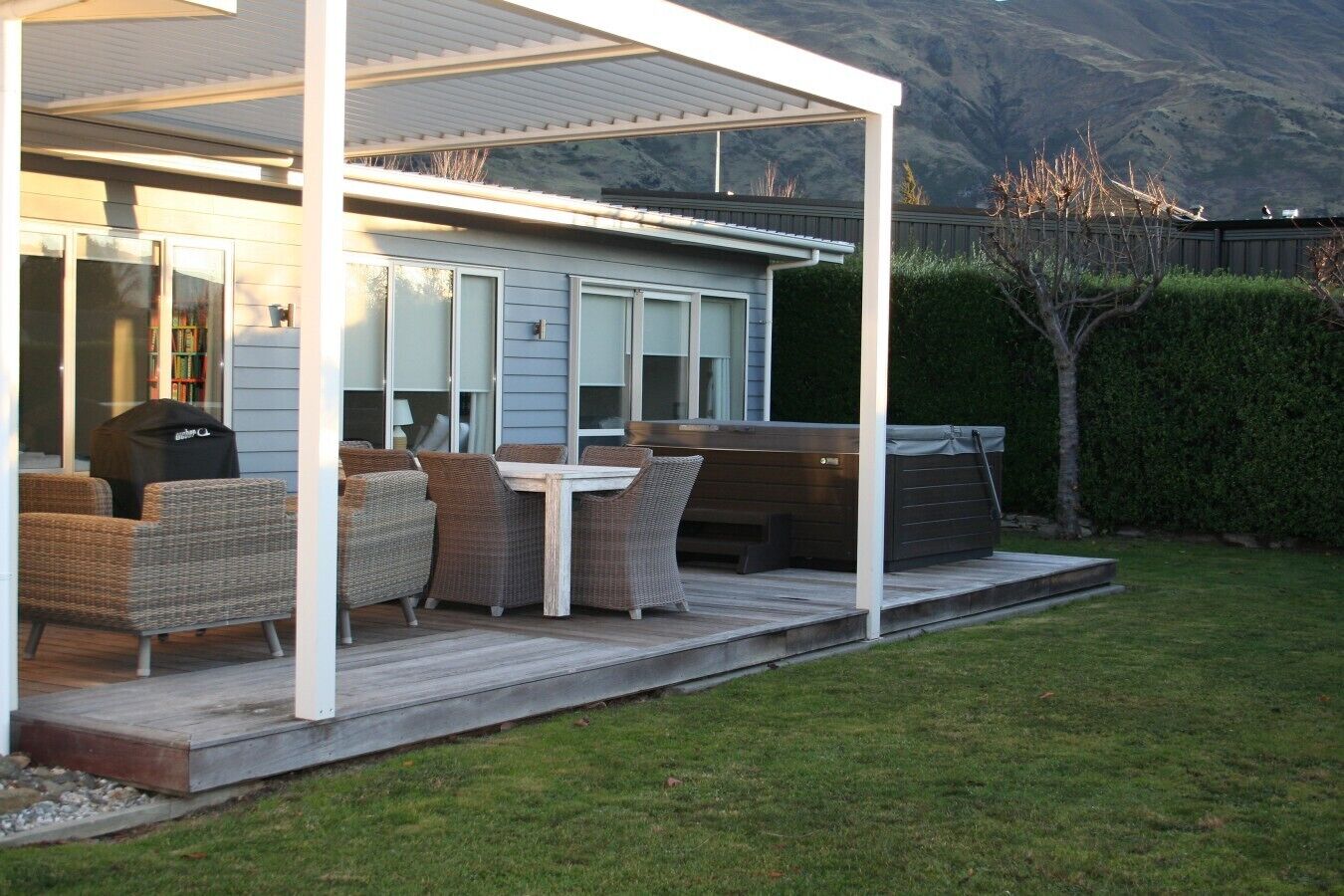 Un patio cubierto con muebles de exterior, una parrilla y vistas a la montaña.