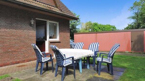 Een terras met een tafel en stoelen, een bakstenen huis en een houten omheining.