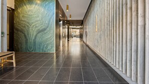 Ein moderner Flur mit Marmorwand, einer Bank und einer Wand mit Säulen.