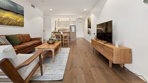 Ein modernes Wohnzimmer mit einer braunen Ledersofa, einem Holztisch und einem Fernseher auf einem Holzschrank.