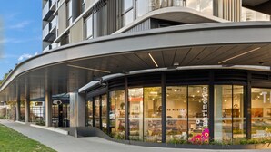 Ein modernes Gebäude mit einer geschwungenen Fassade und großen Glasfenstern, die Möbel zeigen.