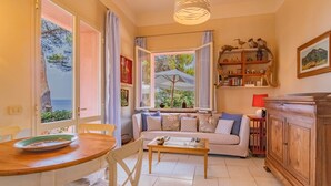 Ein gemütliches Wohnzimmer mit Sofa, Esstisch und Meerblick durch große Fenster.