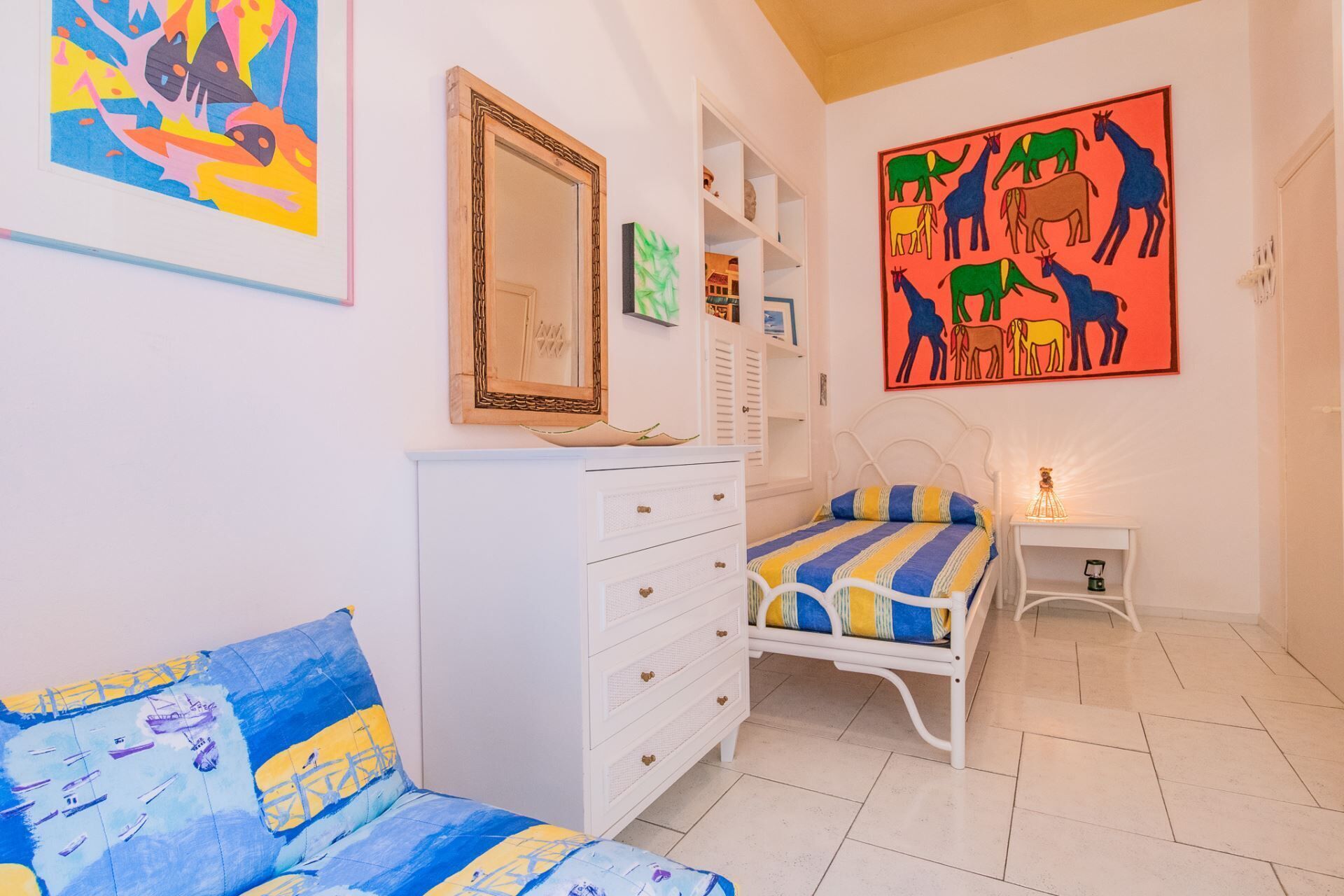 Una camera da letto con un letto, una cassettiera, un comodino e opere d'arte alle pareti.