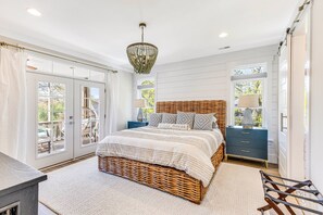 A bedroom with a wicker bed, a nightstand, a dresser, and a chandelier.