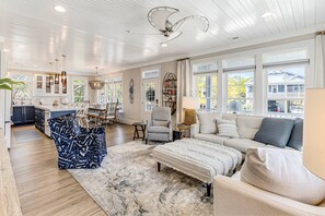 A spacious living room with a large sofa, a coffee table, and a dining area with chairs and a table.