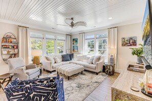 A living room with a sectional sofa, a coffee table, a side table, a bookshelf, and a ceiling fan.