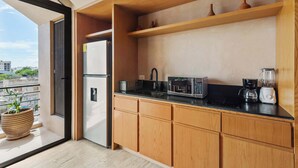 Een moderne keuken met houten kastjes, een zwart aanrecht, een inbouwmagnetron en een koffiezetapparaat.