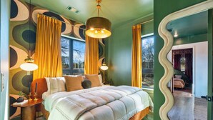 Quarto com uma cama grande, duas luminárias de cabeceira e vista para o exterior através de uma janela.