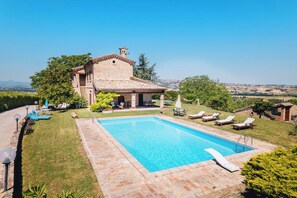 Una villa con piscina, mobiliario de exterior y vistas al campo.