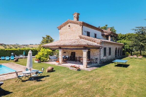 A two-story house with a patio, outdoor seating, and a swimming pool.