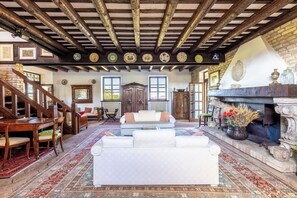 A traditional room with a fireplace, a sofa, a wooden staircase, and a patterned rug.