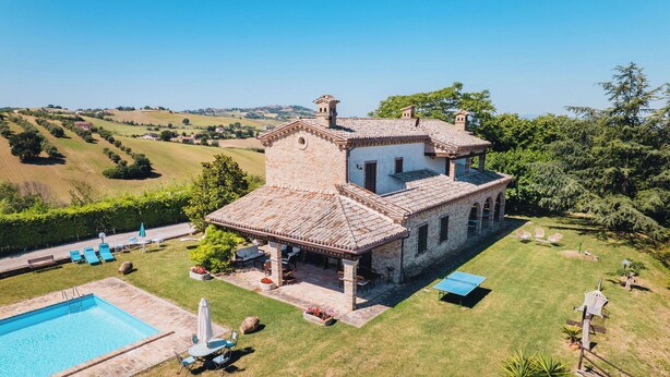 A large house with a swimming pool, outdoor seating, and a view of the countryside. - Italian Experience- Villa Incanto (Potenza Picena)