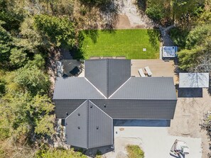 Una casa moderna con techo inclinado, una terraza y un pequeño jardín.