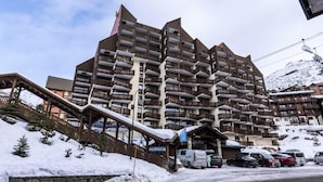 A multi-story hotel with balconies, a ski lift, and a snowy mountain backdrop. - Holiday Home in Val Thorens Ski Area (Les Belleville)
