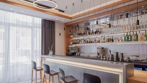 A modern bar area with a bar counter, stools, and a variety of bottles.